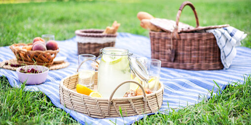 Beatiful picnic on blue blanket with lemonade in foreground